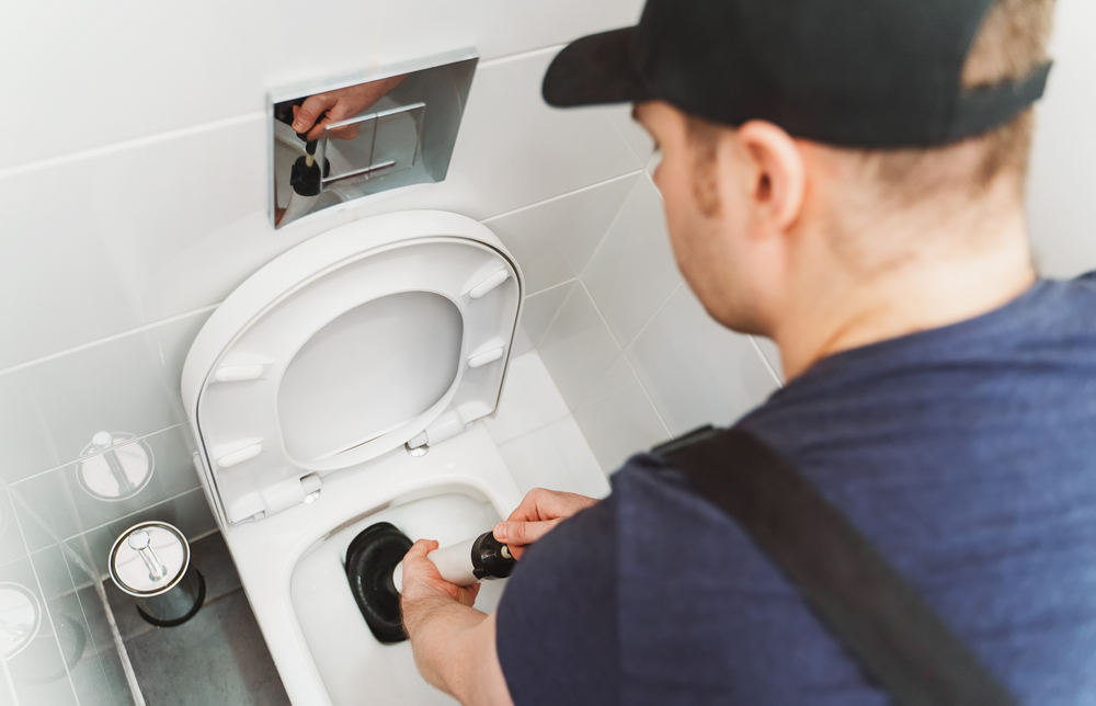 Blue Collars Plumber fixing clogged toilet from tampons